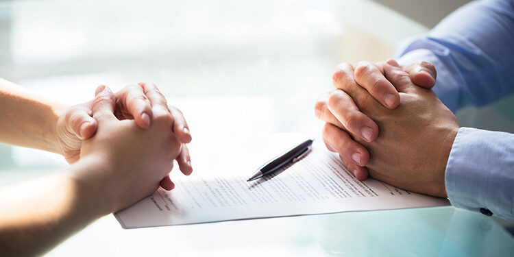 Close-up Of Two Businesspeople Hand With Document On Desk