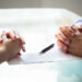 Close-up Of Two Businesspeople Hand With Document On Desk