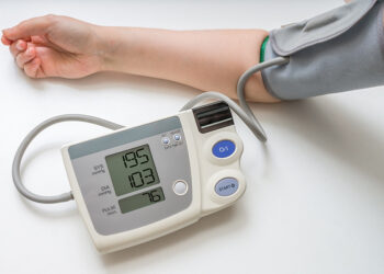 Hypertension concept. Man is measuring blood pressure with monitor. Isolated on white background.