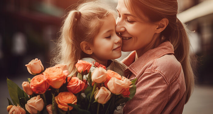 Little girl holding flowers, hugging her mother and celebrating mother's day.