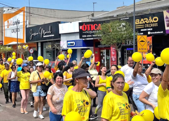 Grupo de moradores do Tatuquara em Curitiba usando camisetas amarelas em caminhada de conscientização do Setembro Amarelo.