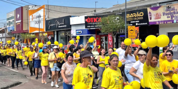 Grupo de moradores do Tatuquara em Curitiba usando camisetas amarelas em caminhada de conscientização do Setembro Amarelo.
