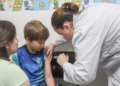 Profissional de saúde aplicando vacina em criança no Dia D de Multivacinação em uma unidade de Curitiba.