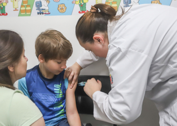 Profissional de saúde aplicando vacina em criança no Dia D de Multivacinação em uma unidade de Curitiba.