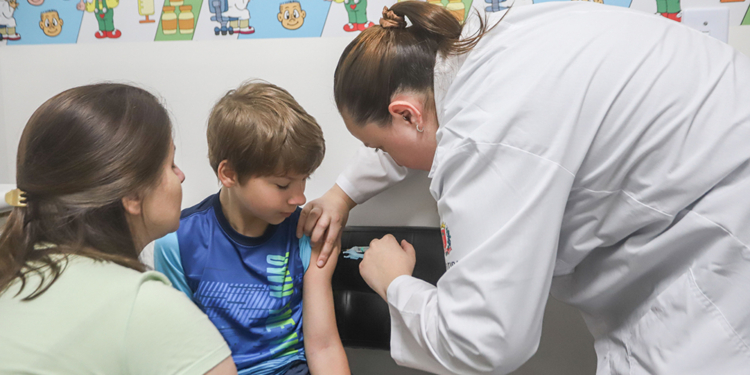 Profissional de saúde aplicando vacina em criança no Dia D de Multivacinação em uma unidade de Curitiba.