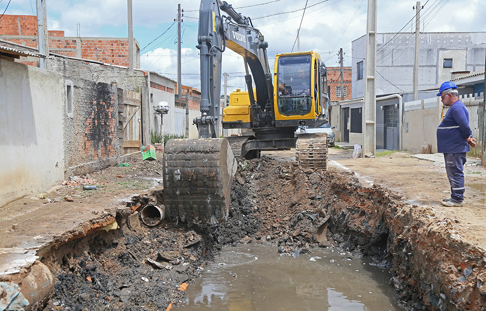 Obras de escavação e pavimentação em uma das ruas do Bairro Caximba, em Curitiba, mostrando a implantação de nova drenagem, asfalto e calçadas.