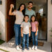 Família com chaves na mão em frente à porta da nova casa própria financiada pelo Minha Casa Minha Vida