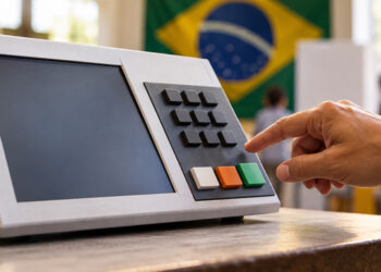 Ilustração de mão de eleitor diante de uma urna eletrônica, com a bandeira do Brasil ao fundo