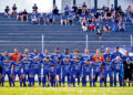 Equipe do Urano posa no gramado com uniformes azuis na estreia da Taça Paraná 2026, com torcedores na arquibancada ao fundo