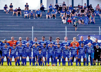 Equipe do Urano posa no gramado com uniformes azuis na estreia da Taça Paraná 2026, com torcedores na arquibancada ao fundo