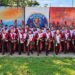 Integrantes da Banda Musical do Caximba uniformizados e com instrumentos diante de um mural em Mairiporã.