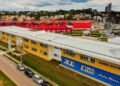 Vista aérea da Rua da Cidadania do Tatuquara, com prédios coloridos e veículos estacionados ao redor.